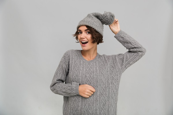 Mujer posando con un suéter y gorro para el frío de color gris piedra, un tono neutro que transmite serenidad