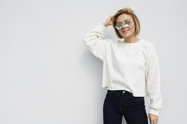 Mujer posando con un suéter de color blanco nieve y un pantalón negro, un estilo que combina elegancia y personalidad