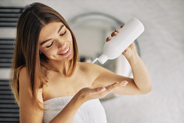Champú sin parabenos - Mujer utilizando un champú líquido para lavar su cabello y remover la suciedad del cuero cabelludo