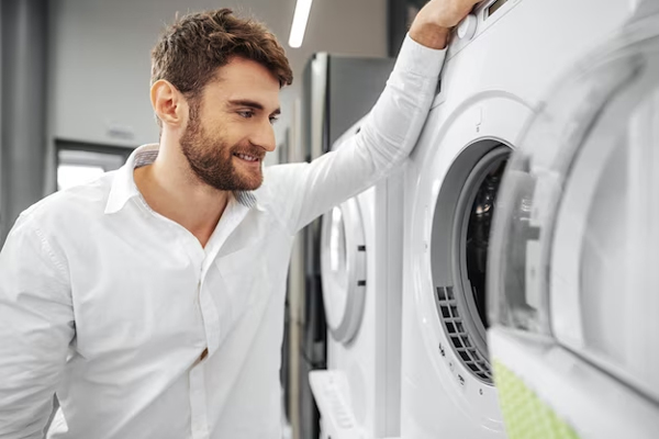 Lavanderías autoservicio en Barcelona - Hombre sonriente se detiene a evaluar la capacidad de carga de una lavadora- secadora en lavandería automática Barcelona