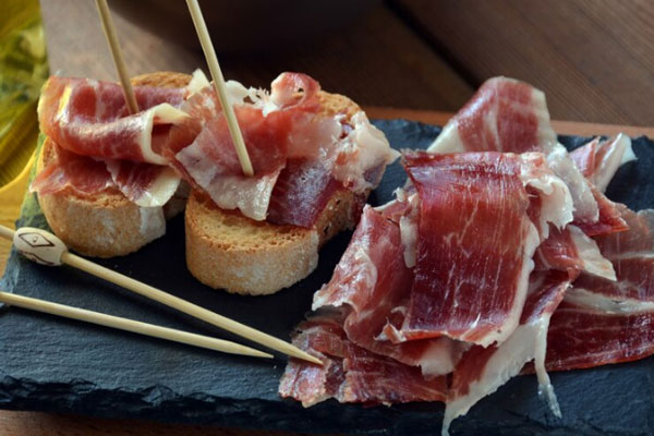 Ciudades gastronómicas de España - Aperitivo de jamón serrano con pan asado como parte de la oferta de tapas de Granada