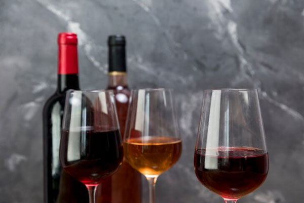 Plano detalle de botellas y una fila con tres copas de vino 