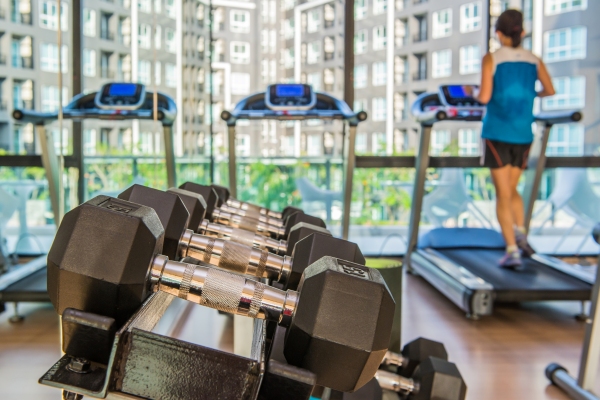 Gimnasios en Madrid - Fila de pesas y vista panorámica de una mujer haciendo caminadora en el mejor gimnasio de Madrid