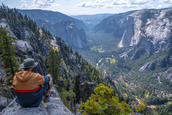 Excursiones - Hombre sentado sobre la roca de una montaña observando el paisaje
