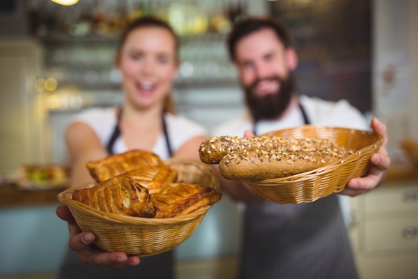 Panaderías - Hombre y mujer sosteniendo en sus manos una cesta con panes horneados en la mejor panadería de Madrid