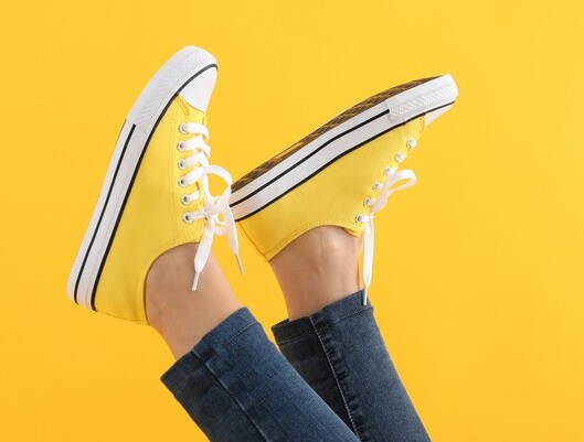 Tiendas de calzado deportivo - Persona con los pies en alto mostrando sus zapatillas de deporte color amarillo compradas en Madrid