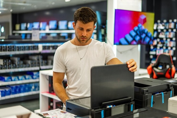 Hombre en tienda de computadores en Barcelona revisando una impresora moderna