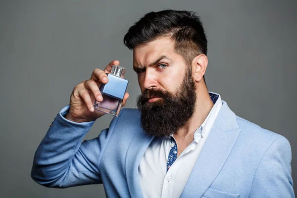 Hombre con barba se aplica un toque de colonia para potenciar su atractivo natural