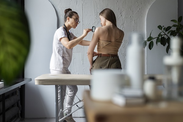 Clínicas dermatológicas de Madrid - Doctora usando una lupa para evaluar la piel de una mujer joven en una de las mejores clínicas estéticas Madrid