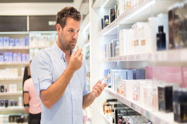 Tiendas de perfume en Madrid - Hombre rubio toma un frasco de perfume para oler su fragancia antes de comprarlo en una tienda de Madrid