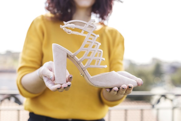 Mujer sosteniendo en sus manos un zapato de tacón alto color rosado