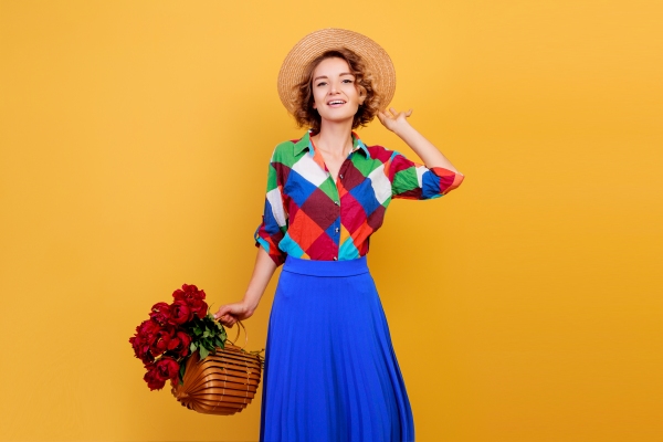 Tendencias primavera verano 2024 - Mujer posando con prendas en tendencia de colores vibrantes mientras sostiene una cesta de flores