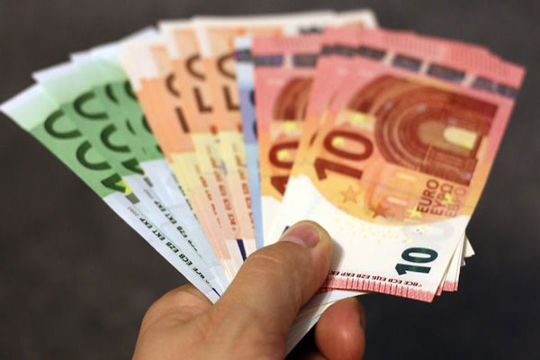 Letras del Tesoro - Hombre sostiene manojo de euros de distintas denominaciones con una mano 