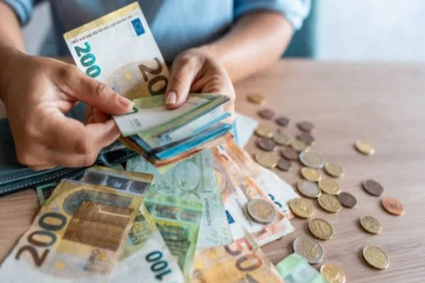 Letras del Tesoro - Mujer cuenta con detenimiento sus ahorros de euros en billetes y en monedas 