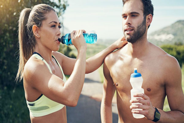 Electrolito bebida sin azúcar en España - Pareja en ropa deportiva hace una para a mitad de camino para reponer energías y seguir trotando