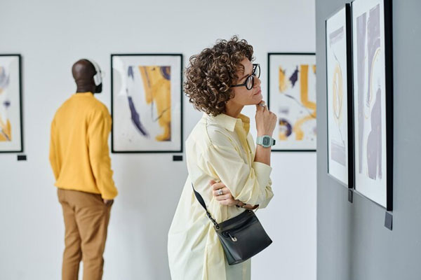 Museos gratis de Madrid - Pareja de jóvenes se detiene a apreciar parte de la obra de un pintor en una galería