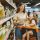 Supermercados en Madrid - Mujer joven sonriendo mientras lleva a una niña sentada en el coche de compras del supermercado en Madrid