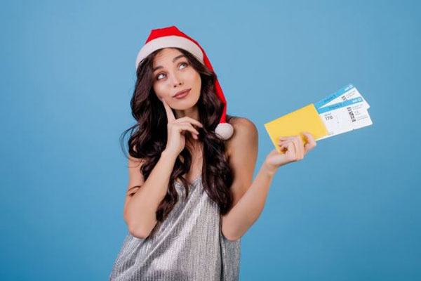 Regalos de navidad - Mujer con gorro de Santa Claus planea regalar un viaje en las festividades de diciembre 