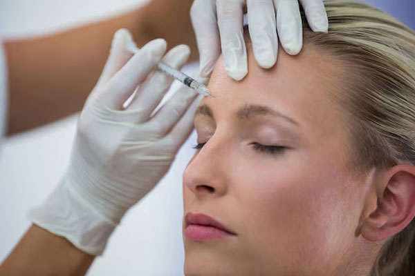 Mujer recibe tratamiento facial para suavizar las arrugas de la frente