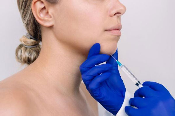 Dermatólogo infiltra una sustancia reabsorbible para mejorar la definición del mentón en una mujer joven