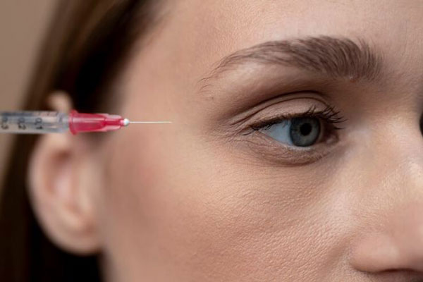Plano detalle de una mujer joven recibiendo un tratamiento estético para mejorar la apariencia de las ojeras