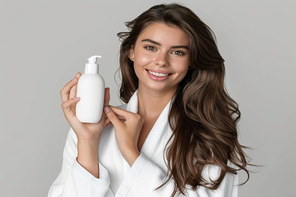 Champú hidratante - Mujer mostrando en sus manos un recipiente de champú hidratante sin sulfatos ni silicona que revitaliza el pelo