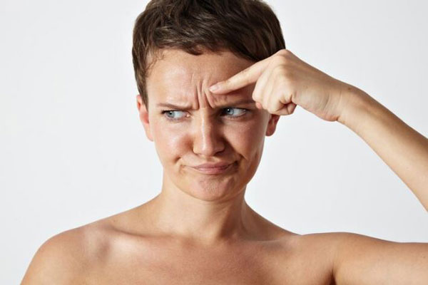 Bótox y ácido hialurónico - Mujer joven con el ceño fruncido busca soluciones estéticas para atenuar líneas de expresión mediante bótox Barcelona