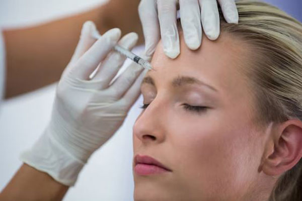 Bótox y ácido hialurónico - Dermatólogo aplica una inyección de bótox Madrid para tensar las arrugas del entrecejo en una mujer