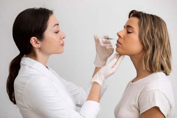 Bótox y ácido hialurónico - Dermatóloga aplicando rellenos con bótox Barcelona para mejorar el volumen de los labios de una paciente