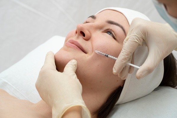 Esteticista aplicando una inyección para el tratamiento de mesoterapia facial en una mujer