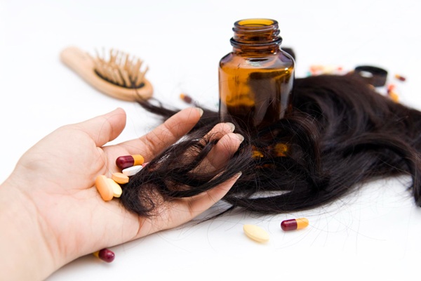 Complementos vitamínicos para la caída del pelo - Persona sosteniendo en su manos vitaminas para el cabello que evitan la caída del pelo a causa de la alopecia