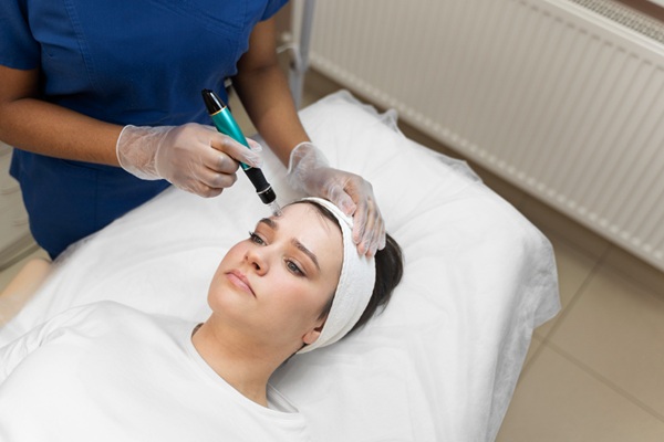 Dermapen - Esteticista realizando un tratamiento dermapen facial a una mujer joven en una de las mejores clínicas estéticas Madrid