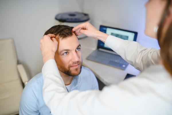 Médico tricólogo evaluando a un hombre con alopecia de manera personalizada
