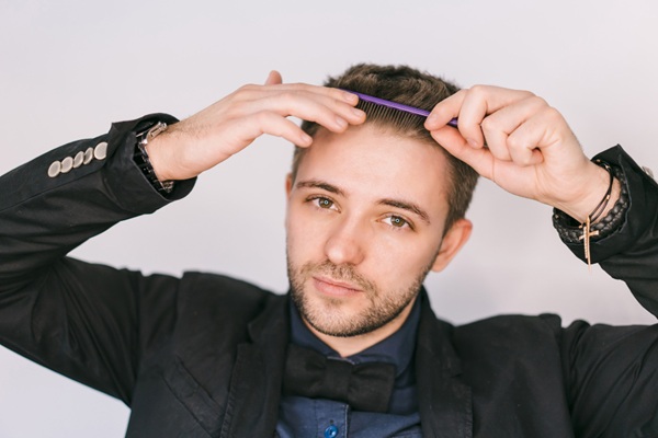 Hombre feliz peinado su cabello abundante y natural luego de un tratamiento de implante de cabello en Turquía