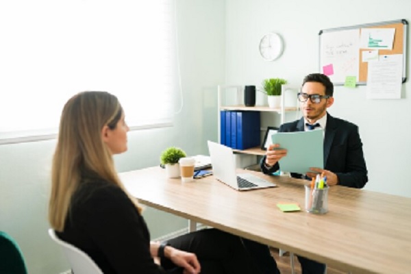 preguntas frecuentes en una entrevista de trabajo- entrevistador revisando la experiencia de chica ejecutiva